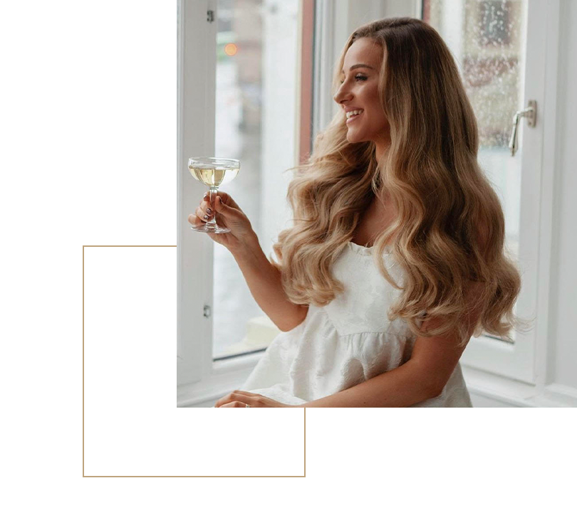 Kvinna njuter av ett glas vin medan hon visar upp sin lyxiga Hairtalk hårförlängning, som faller i perfekta vågor och lyser av hälsa och volym